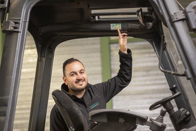 Adviseur van Prevensa wijst op de keuringssticker van een heftruck